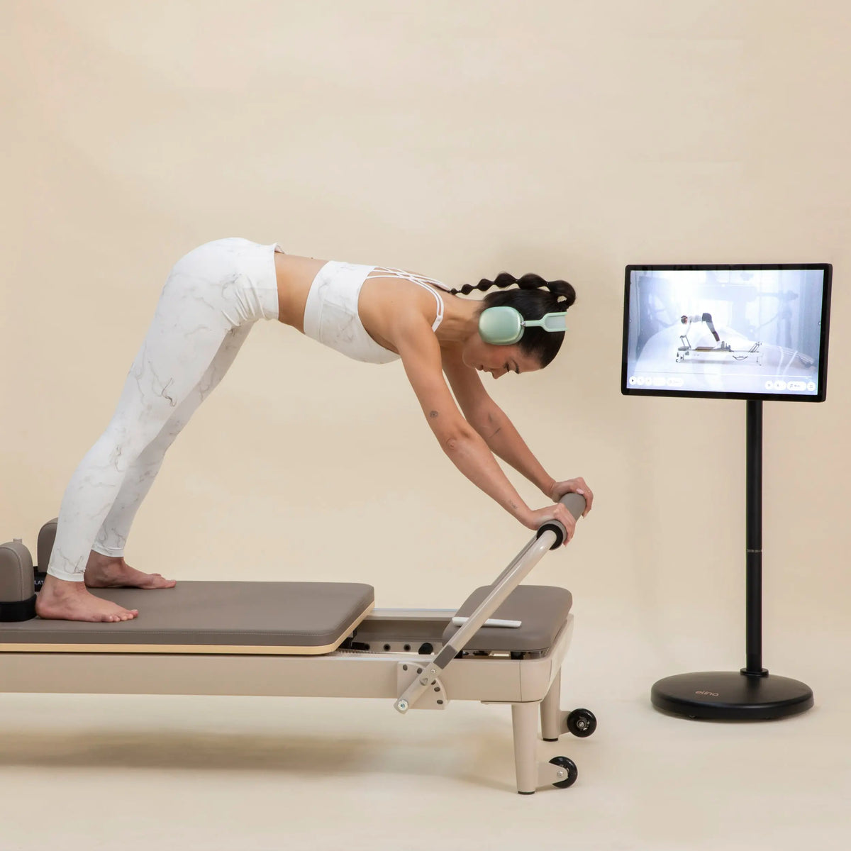 Frau trainiert im Stand auf dem Elina Pilates Nubium Moka Edition Reformer
