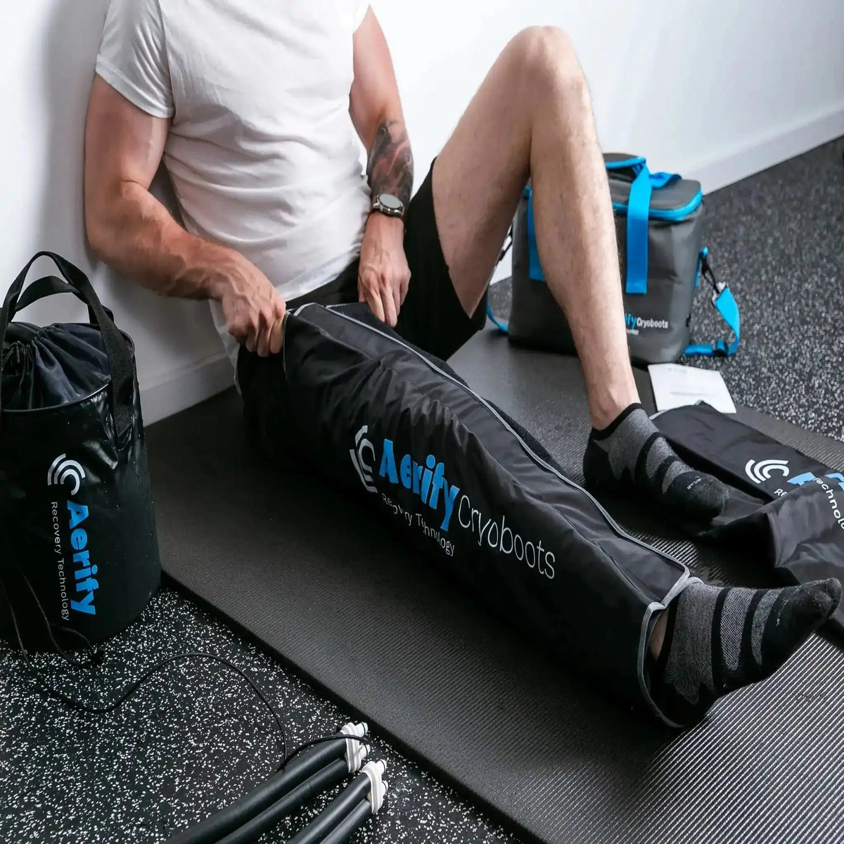Aerify Cryoboots Set im Einsatz: Mann sitzt an der Wand mit beiden Beinmanschetten