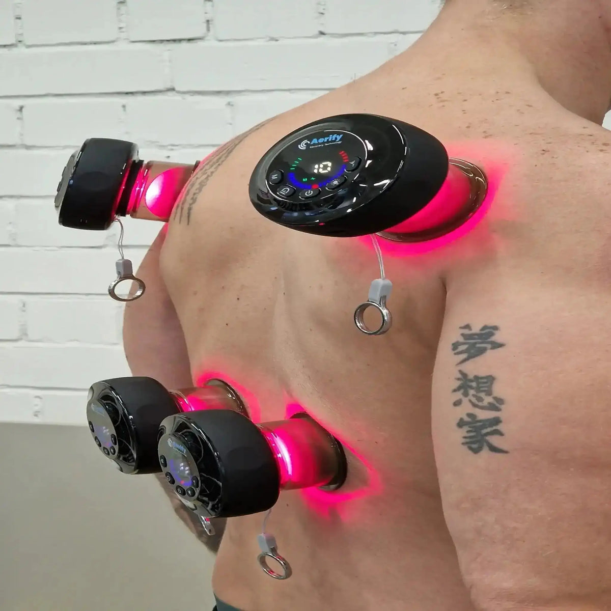 Aerify Dynamic Cupping, zwei Geräte mit rotem Licht auf Schulter und Oberarm eines Mannes