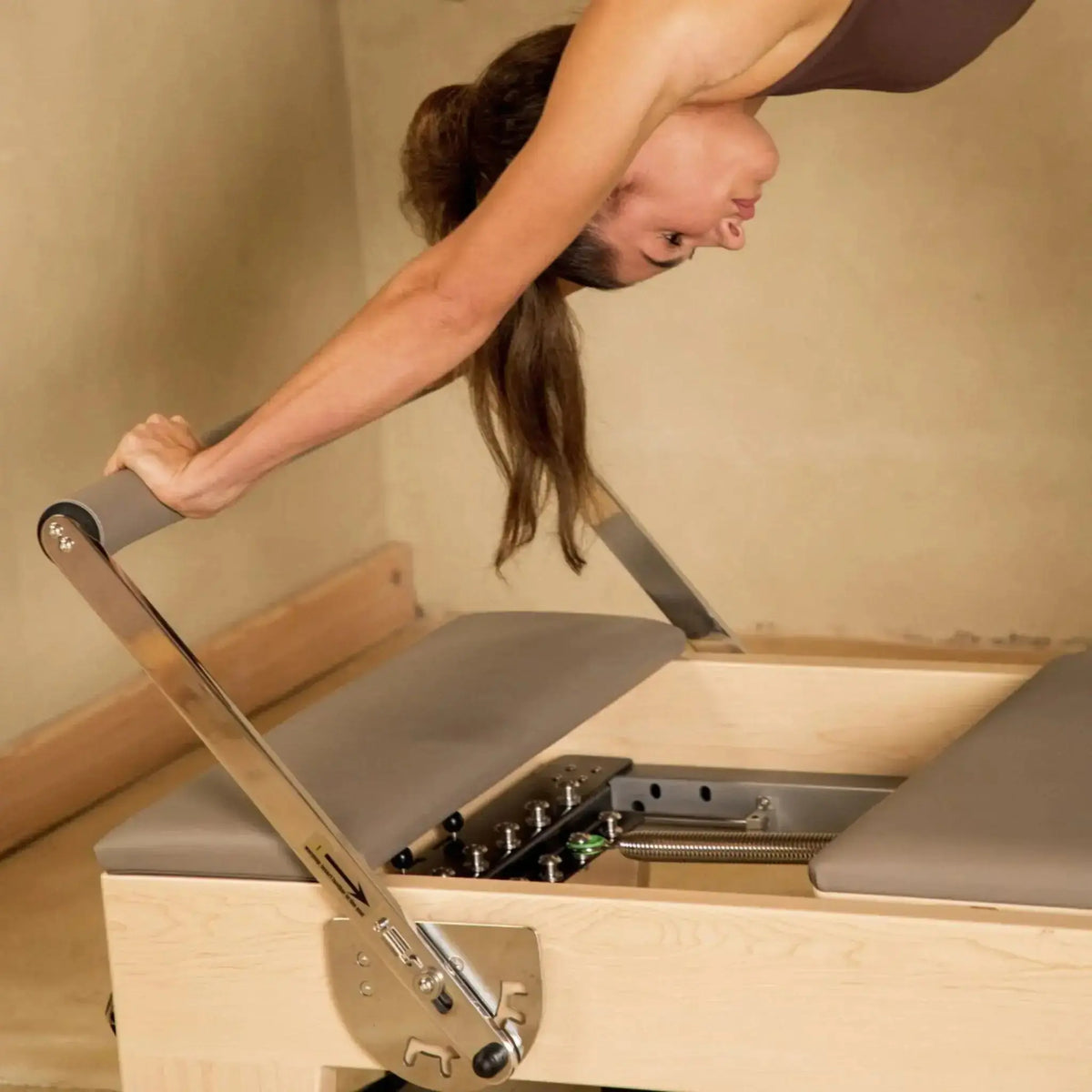 Frau stellt die Fußstange des Elina Pilates Elite Reformers ein