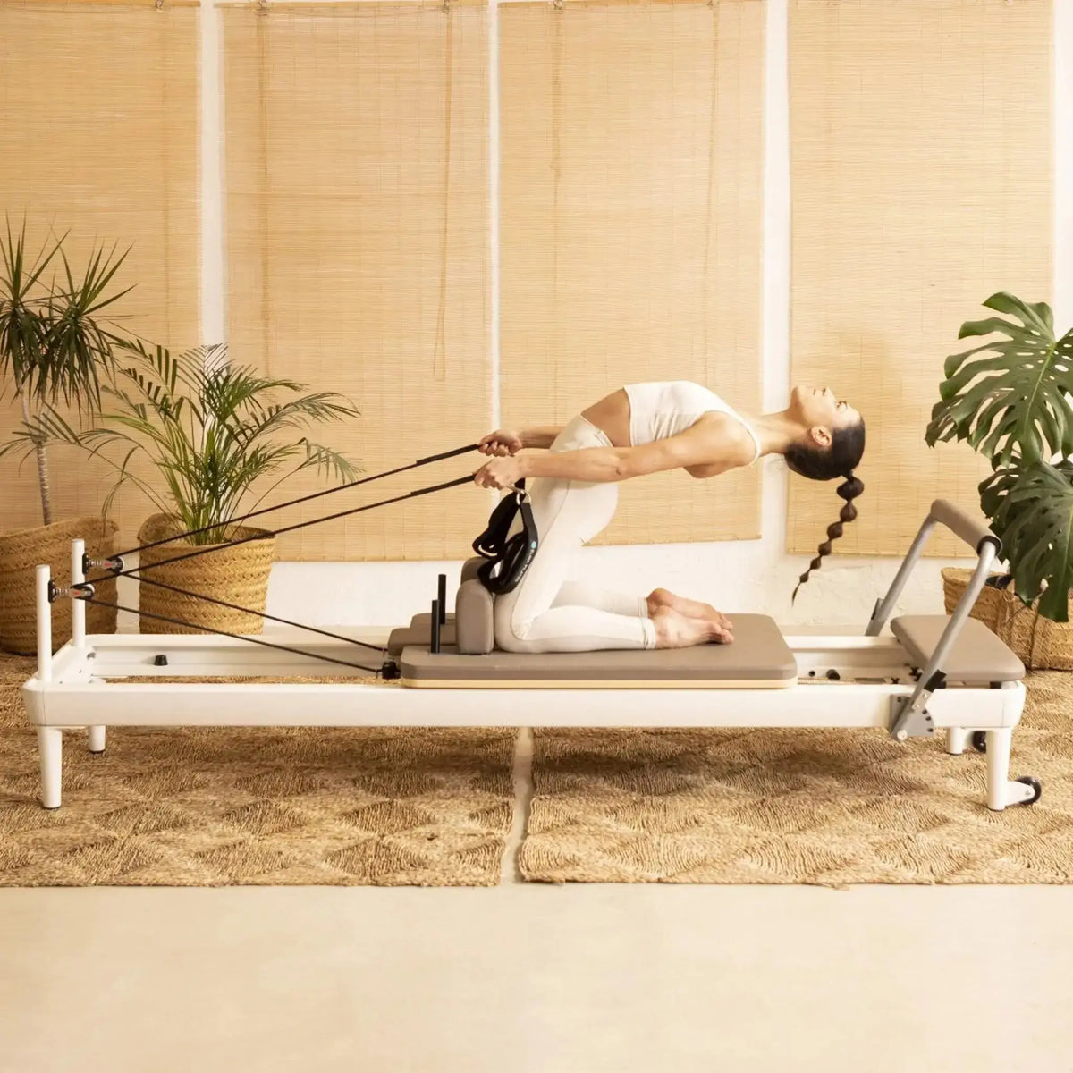 Frau trainiert mit den Seilschlaufen auf dem Elina Pilates Nubium Reformer