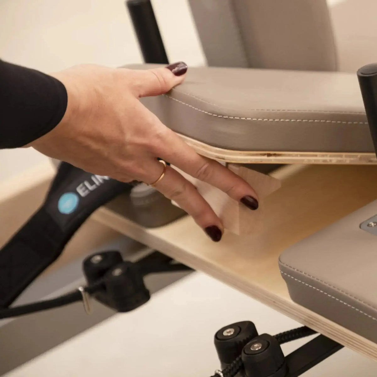 Elina Pilates Master Instructor Reformer aus Ahornholz – Detail: Hand hebt das Polster der Sitzbox an