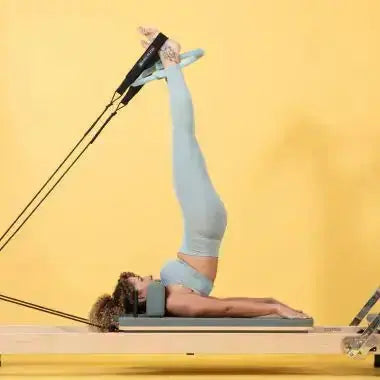 Elina Pilates Pilates-Ring in Hellblau, Frau hält den Ring zwischen den Füßen bei einer Übung auf dem Reformer