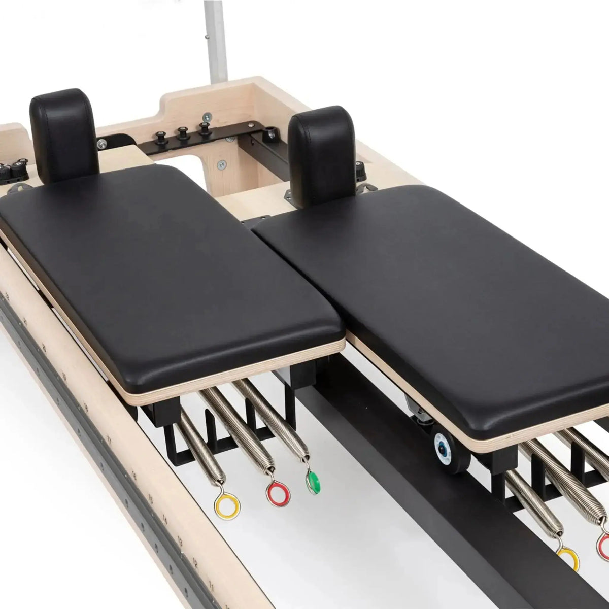 Elina Pilates Twin Reformer aus Ahornholz, Detail der beiden Wagen mit Schulterstützen und farbigen Federn