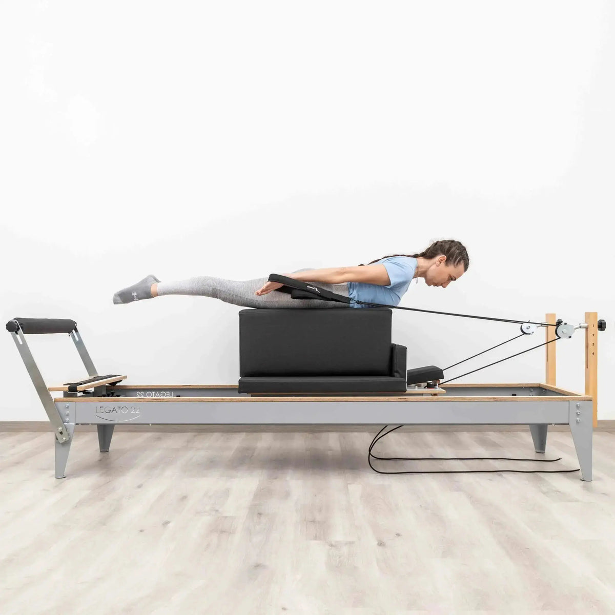 Hegren Pilates Box Modern auf dem Reformer, Frau liegt bäuchlings beim Zugtraining