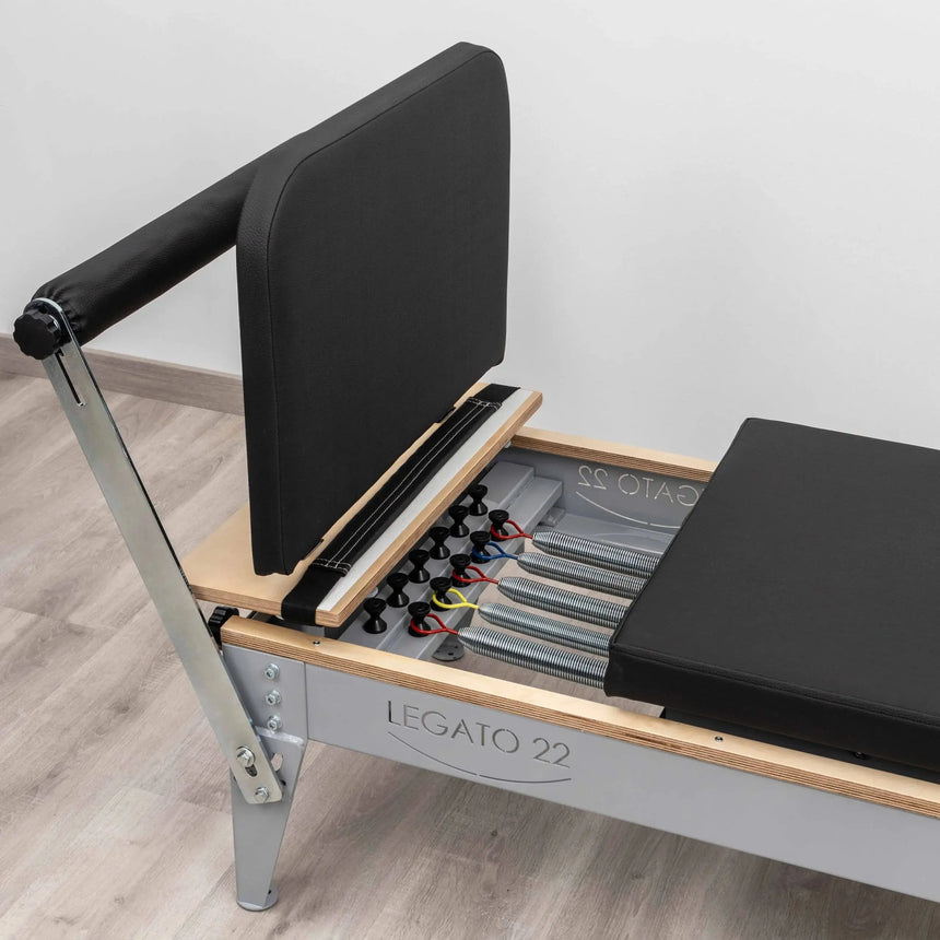 HEGREN Jumpboard LEGATO attached to a Pilates Reformer, showcasing its padded surface and spring-loaded design.