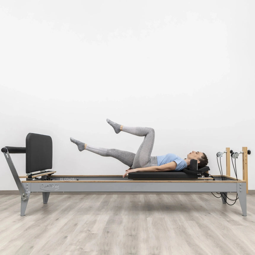 HEGREN Jumpboard LEGATO attached to a Pilates Reformer, showcasing its padded surface and spring-loaded design.