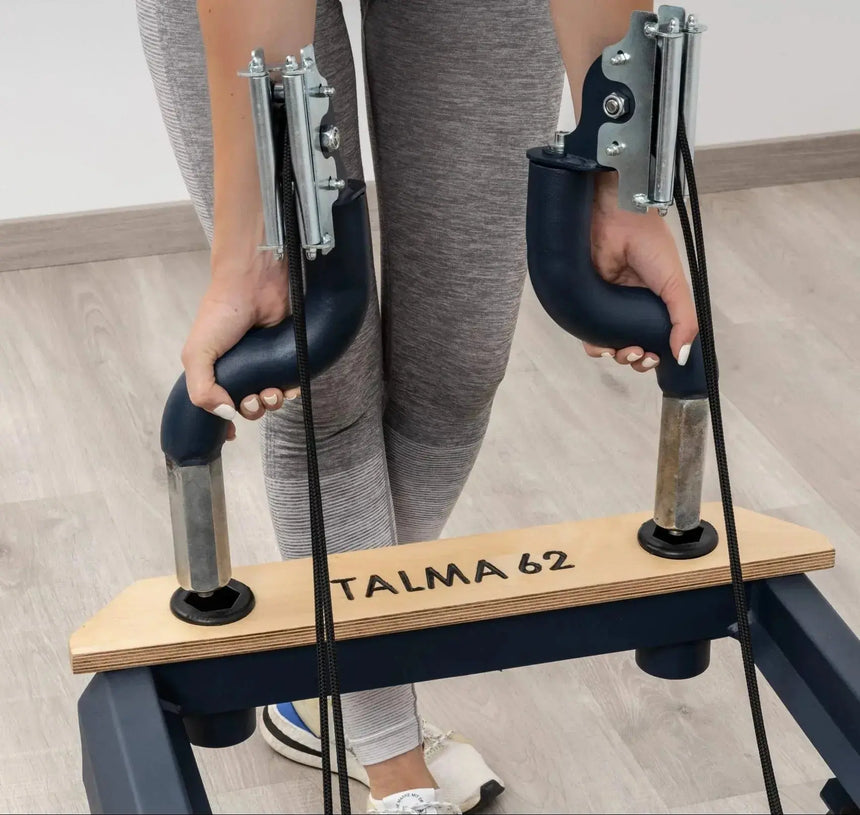 Side view of the HEGREN TALMA 62 Pilates Reformer showcasing its steel frame and beige upholstery.