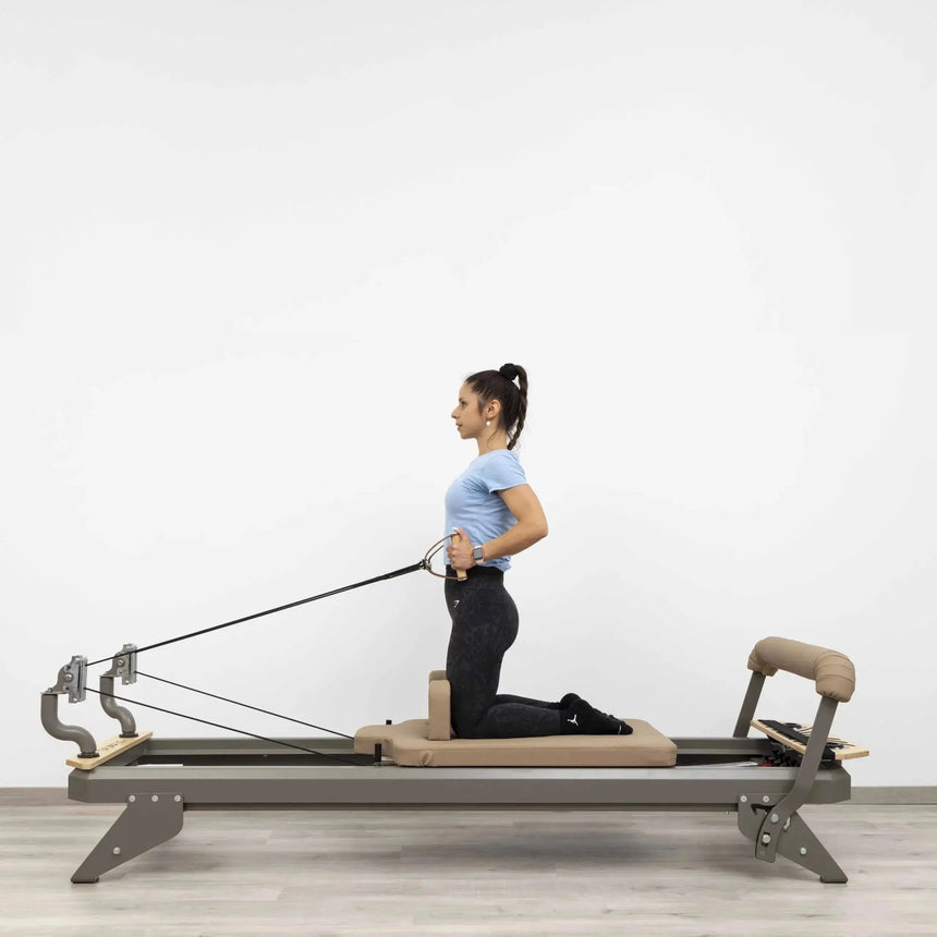 Side view of the HEGREN TALMA 62 Pilates Reformer showcasing its steel frame and beige upholstery.