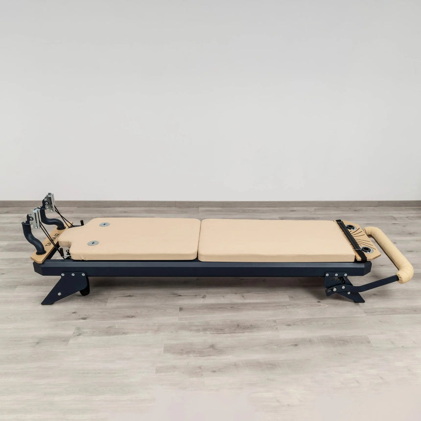 HEGREN Mat Converter TALMA placed on a Pilates Reformer, showcasing its cushioned surface and beige upholstery.