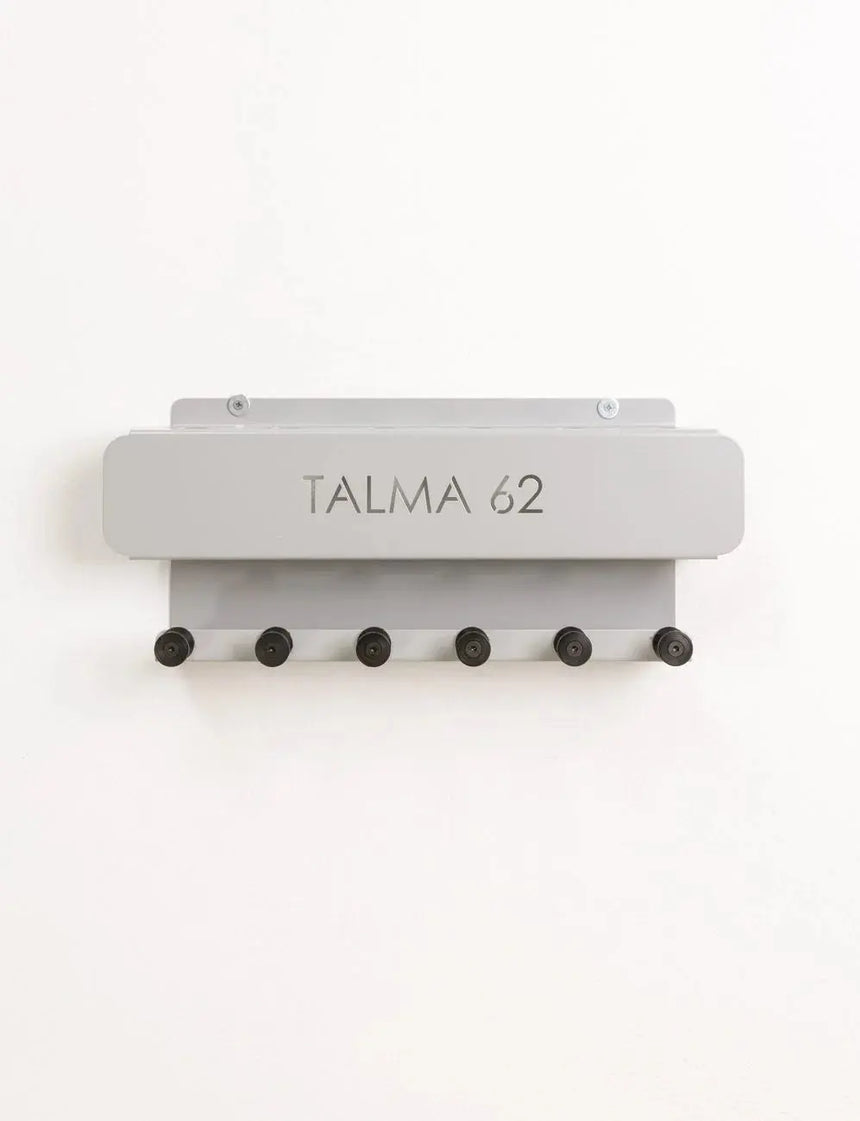 Wall-mounted HEGREN Pilates Stick Stand with 6 slots and 6 hooks for organized storage of Pilates sticks and accessories.