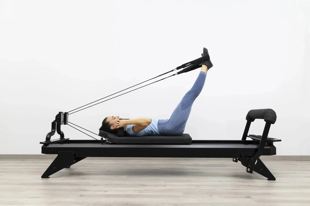 Hegren TALMA 62 Black Elegance Reformer mit Frau in Rückenlage beim Beinzug, Seitenansicht