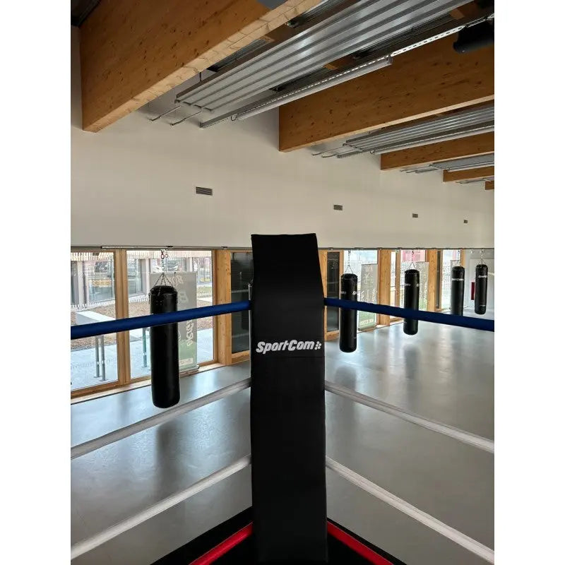 SportCom Eckpolster-Set für Boxringe mit 4 Seilen, schwarzes Eckpolster mit Logo, Blick über den Ring in die Halle