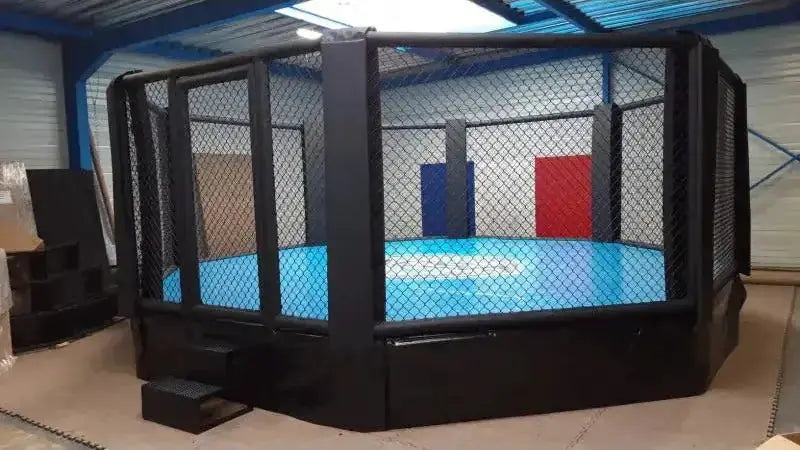 SportCom MMA-Käfig Oktagon mit Podium, mit blauer Matte und Treppe in der Halle