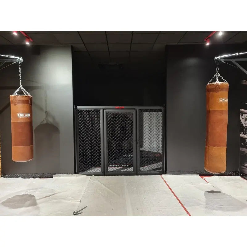 SportCom MMA-Paneel mit Tür als Käfigfront zwischen zwei braunen Boxsäcken
