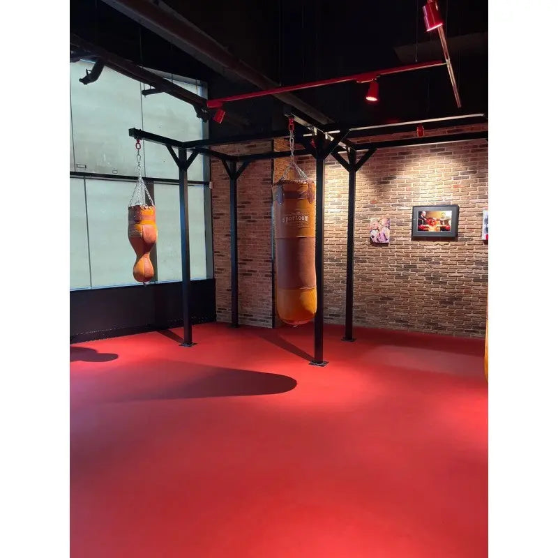 SportCom Proboxe Wandstation für Sandsäcke, auf rotem Boden vor Backsteinwand