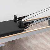  Side view of the HEGREN Pilates Reformer LEGATO 22 showcasing its steel frame and black upholstery.
