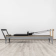  Side view of the HEGREN Pilates Reformer LEGATO 22 showcasing its steel frame and black upholstery.