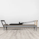 Side view of the HEGREN Pilates Reformer LEGATO 22 showcasing its steel frame and black upholstery.