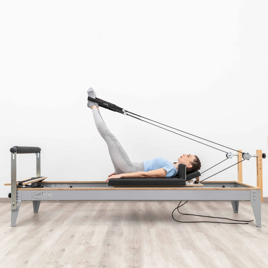  Side view of the HEGREN Pilates Reformer LEGATO 22 showcasing its steel frame and black upholstery.