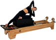 Woman using a Pilates reformer machine on a white background