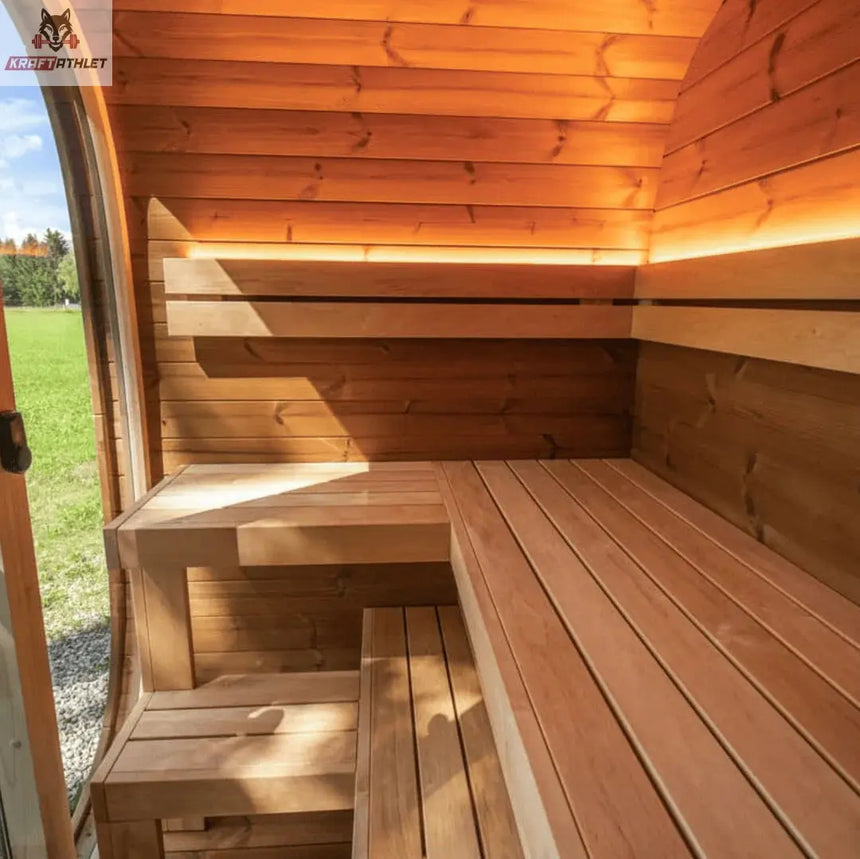 Wooden sauna interior with benches and a view of grass outside.