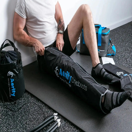Aerify Cryoboots Set im Einsatz: Mann sitzt an der Wand mit beiden Beinmanschetten