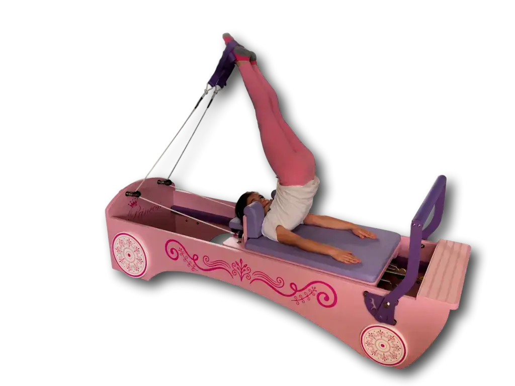 Body & Exercise Reformer Kid in Rosa mit Kind bei einer Übung an den Schlaufen vor schwarzem Hintergrund