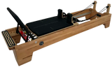 Body & Exercise Reformer Studio P001 aus Buchenholz, Schrägansicht mit schwarzem Schlitten und Federn