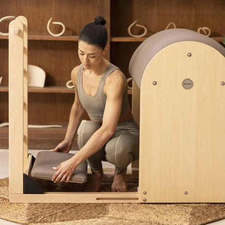 Frau richtet das Polster der Fußplattform am Elina Pilates Elite Ladder Barrel