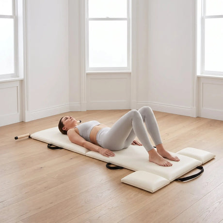 Frau liegt mit angewinkelten Beinen auf der ausgeklappten Elina Pilates Faltmatte in einem Studio