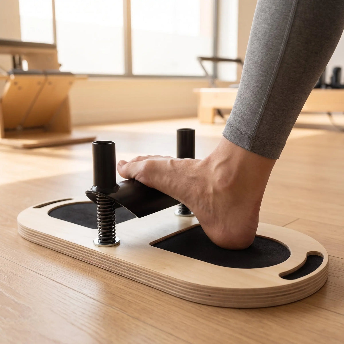 Nackter Fuß auf dem Elina Pilates Foot Corrector, Ferse auf dem Polster, Fußgewölbe über der Stange