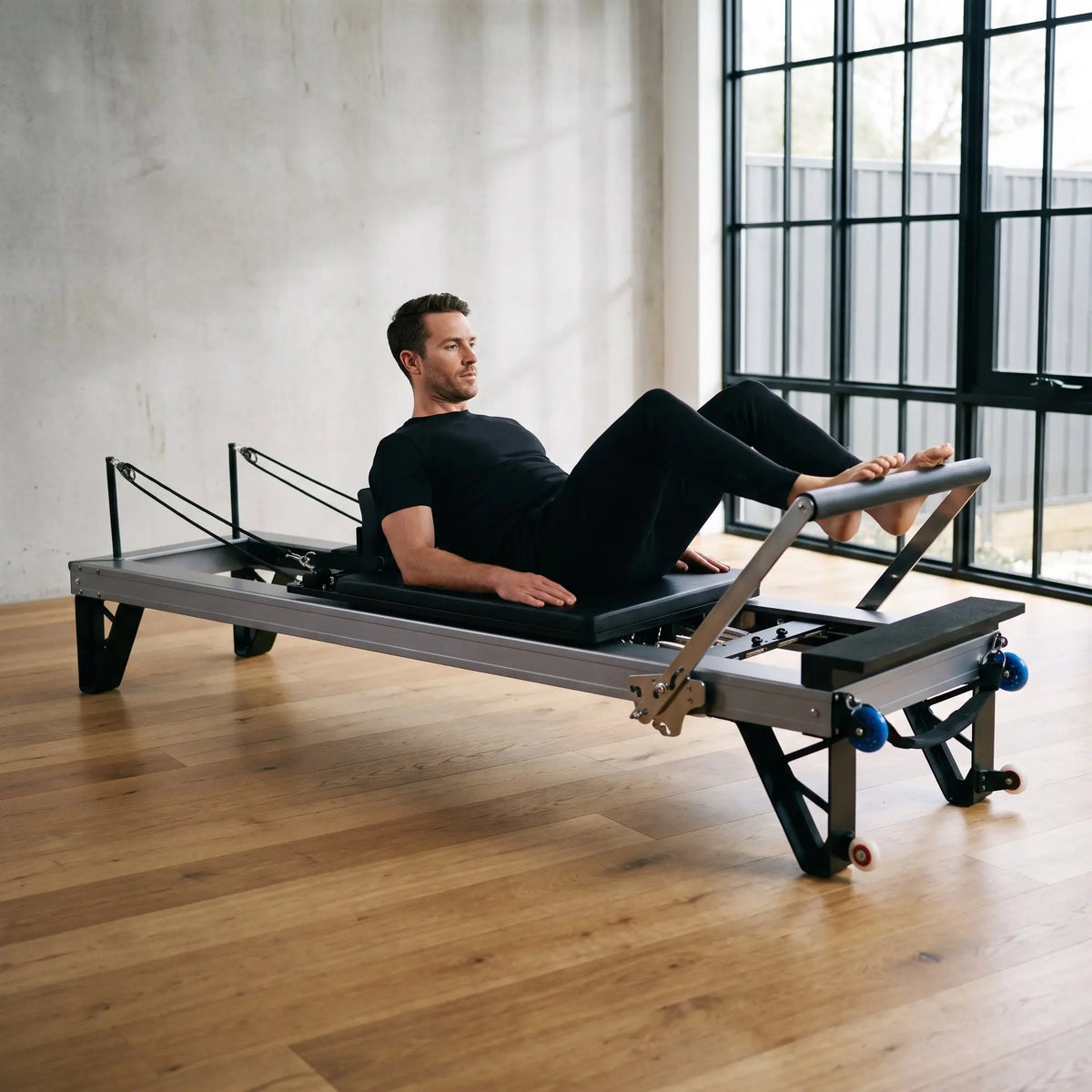 Mann trainiert Fußarbeit auf dem Elina Pilates HL3 Reformer mit eloxiertem Aluminiumrahmen