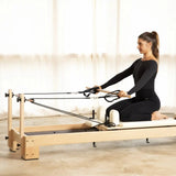 Frau kniet auf dem Elina Pilates Lignum Reformer und zieht die Seilschlaufen