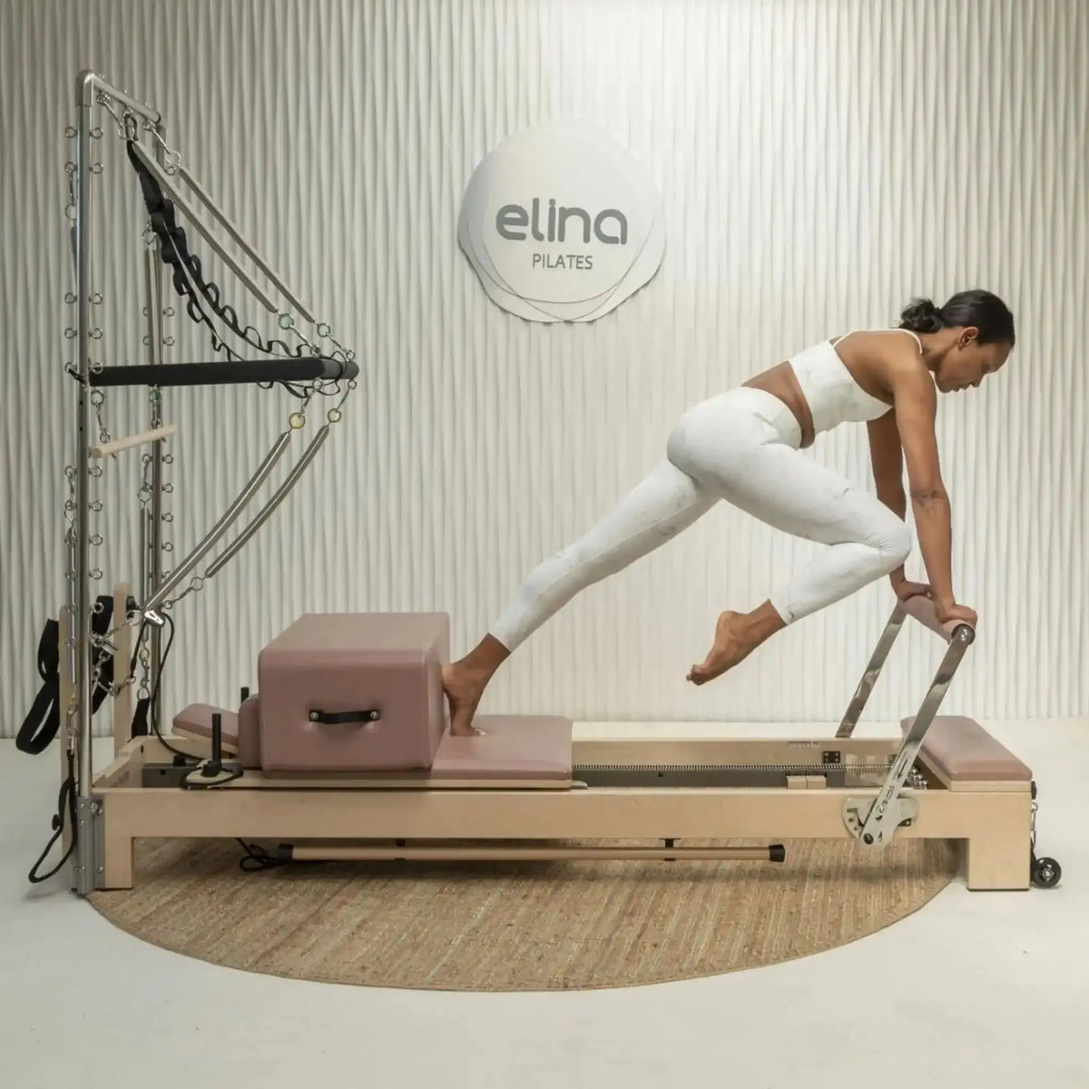 Frau trainiert auf der Sitzbox des Elina Pilates Lignum Reformers in einem Studio