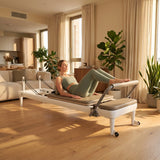 Frau trainiert morgens auf dem Elina Pilates Nubium Reformer mit Aluminiumrahmen im Wohnzimmer