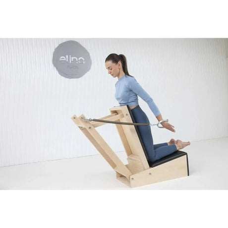 Elina Pilates Baby Chair aus Ahornholz: Frau übt mit gestreckten Armen am Pilates-Stuhl im Studio