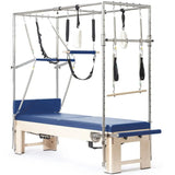 Elina Pilates Cadillac Elite Reformer aus Rock-Ahorn – Schrägansicht mit Ahorngestell und Polstern in Blau