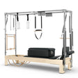 Elina Pilates Cadillac Reformer aus Ahornholz, Seitenansicht mit Polstern in Schwarz und Trapez-Rahmen aus Aluminium