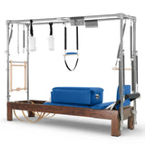 Elina Pilates Cadillac Reformer aus Walnussholz – Schrägansicht mit Stahlrahmen und Polstern in Blau