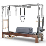 Elina Pilates Cadillac Reformer aus Walnussholz – Schrägansicht mit Stahlrahmen und Polstern in Grau