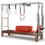 Elina Pilates Cadillac Reformer aus Walnussholz – Schrägansicht mit Stahlrahmen und Polstern in Rot