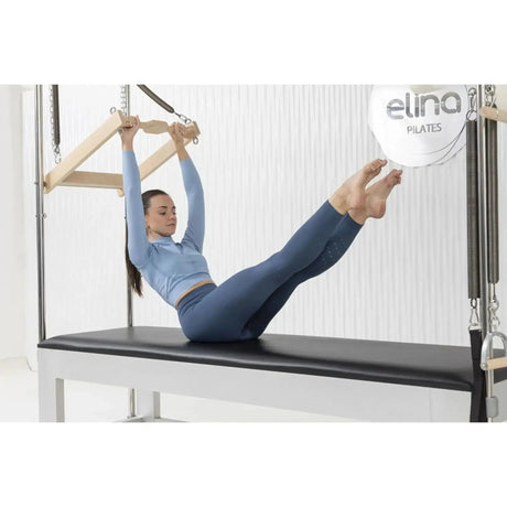 Elina Pilates Classic Cadillac aus Aluminium – Frau trainiert in Rückenlage mit der Trapezstange im Studio