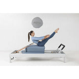 Elina Pilates Classic Reformer aus Aluminium, Frau trainiert im Sitzen mit gestreckten Beinen