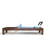 Elina Pilates Classic Reformer aus Walnussholz mit Polstern in Eisblau, Seitenansicht vor weißem Hintergrund
