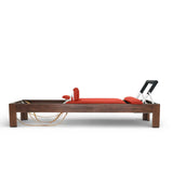 Elina Pilates Classic Reformer aus Walnussholz mit Polstern in Rot, Seitenansicht vor weißem Hintergrund