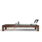 Elina Pilates Classic Reformer aus Walnussholz, Seitenansicht mit Holzrahmen, Federn und Fußstange