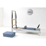 Elina Pilates Classic Reformer mit Tower aus Aluminium – im Studio vor weißer Wand mit blauem Polster und Sitzbox