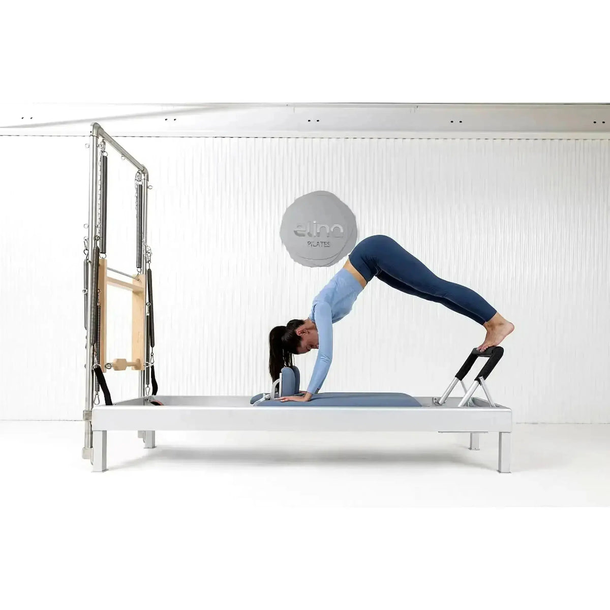Elina Pilates Classic Reformer mit Tower aus Aluminium – Frau in Pike-Position auf dem Schlitten im Studio