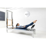 Elina Pilates Classic Reformer mit Tower aus Aluminium – Frau in Rückenlage mit gestreckten Beinen im Studio